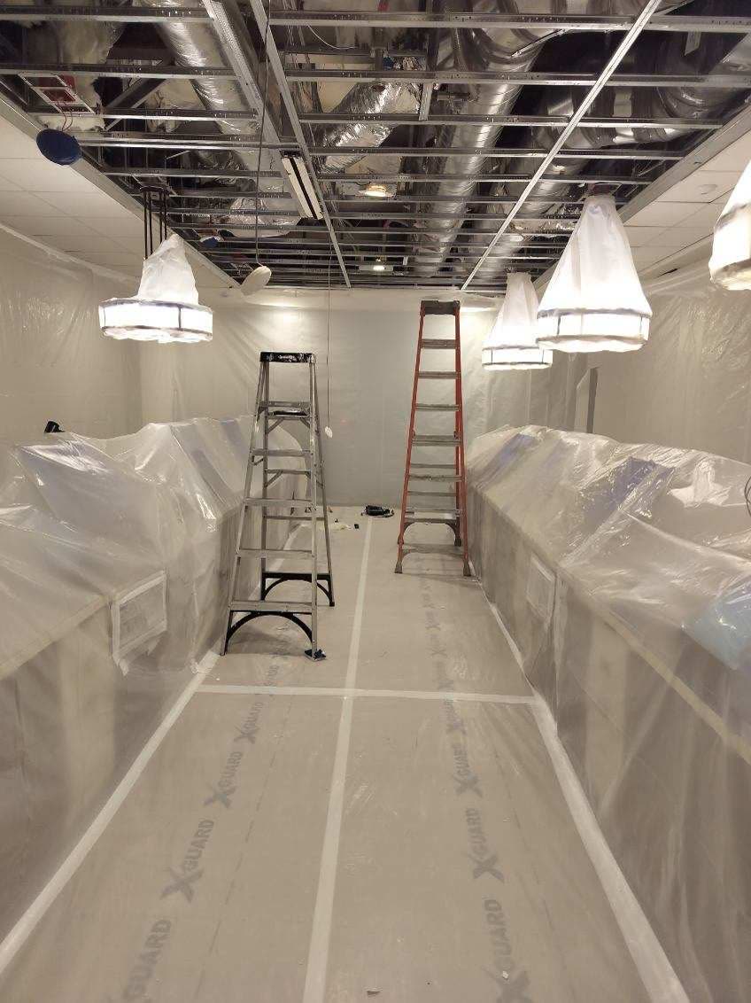 Interior space fully masked with plastic containment and floor protection before work begins