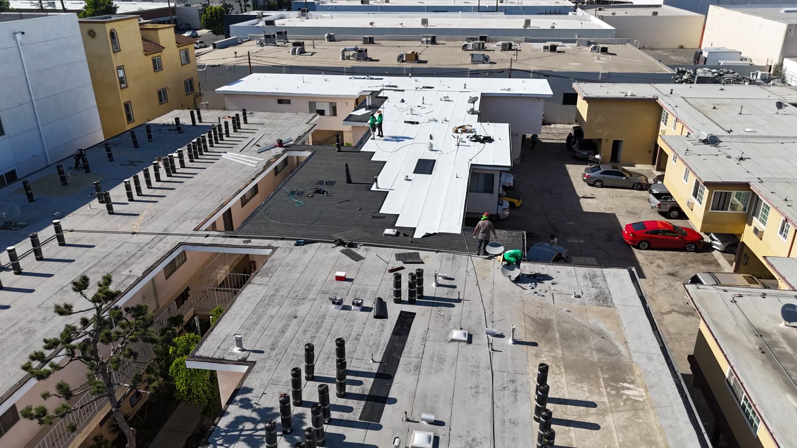 Aerial view of a crew installing a new flat roof membrane on a Los Angeles apartment building