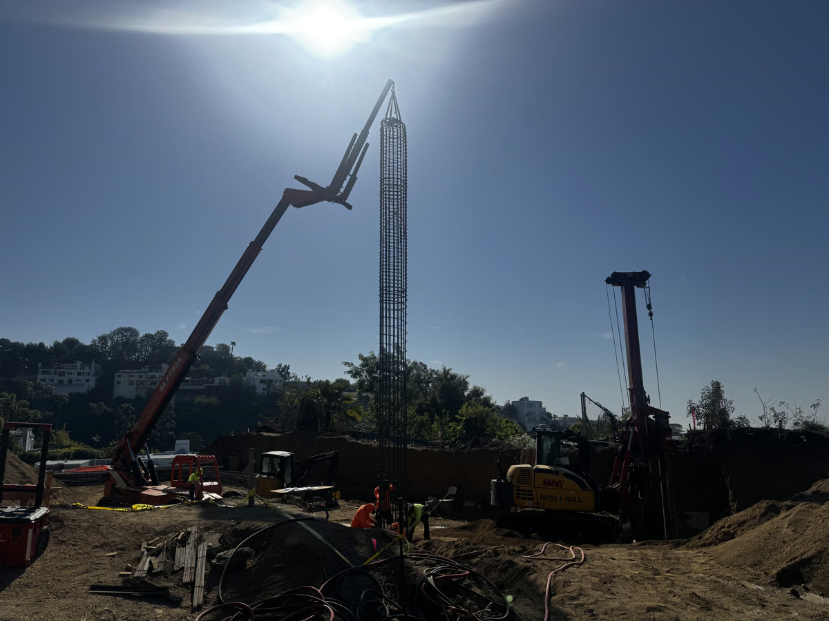 Crane setting a caisson rebar cage on a hillside new construction site