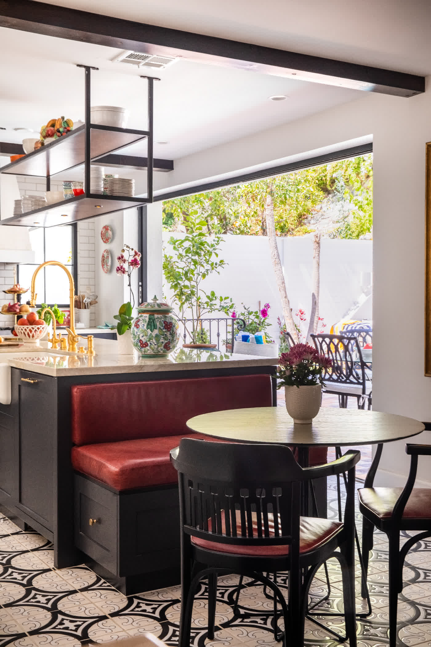 Kitchen breakfast nook with red leather banquette, patterned cement tile floor, and open steel shelving