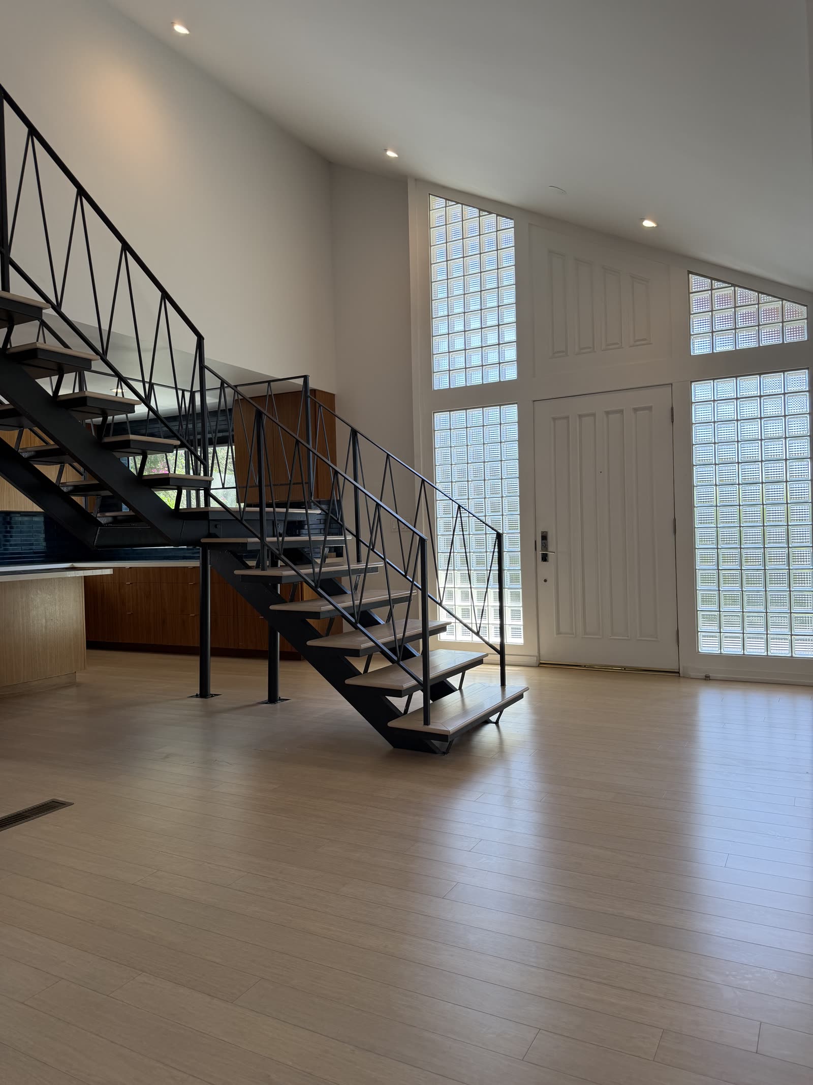 Floating steel and wood staircase in a double-height entry with glass block windows
