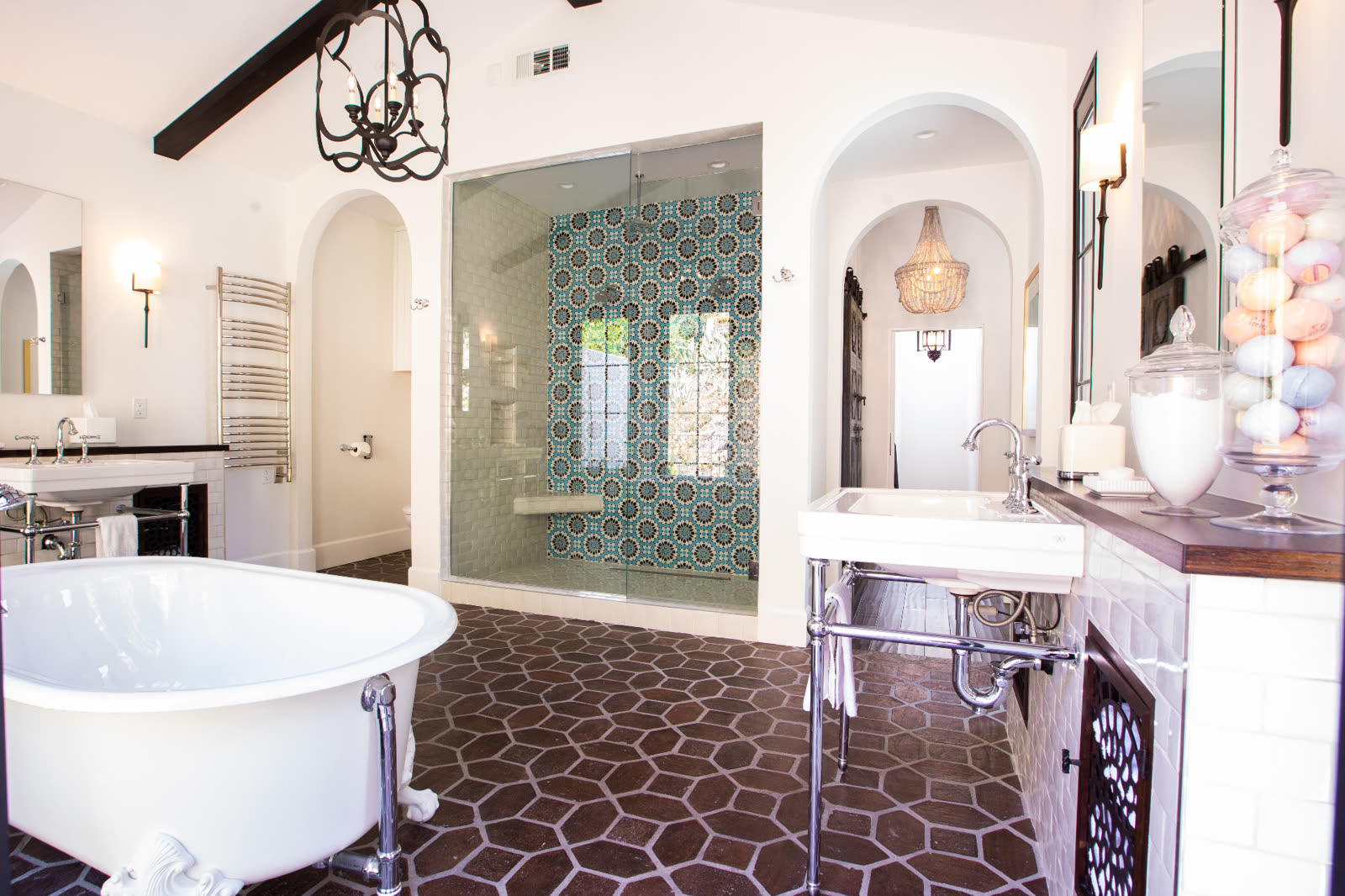 Spanish-style primary bathroom with clawfoot tub, patterned tile shower, and terracotta hex floor